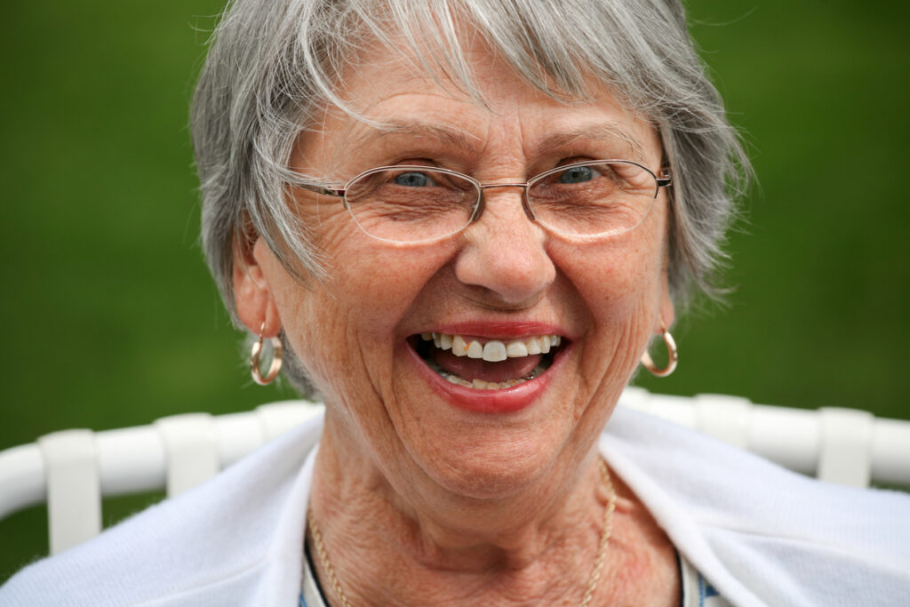 Head and shoulder image of an eighty year old woman showing the beauty of aging with serenity. She is laughing while looking at the camera.