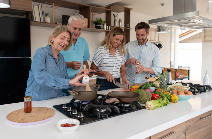 adult children and mom cooking a Father's Day dinner for dad