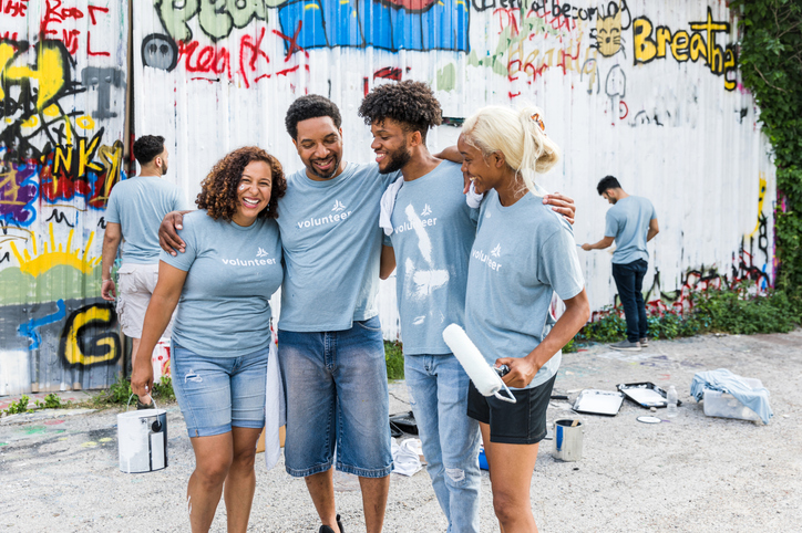 The multiracial family embrace each other in encouragement while they volunteer to celebrate Father's Day.